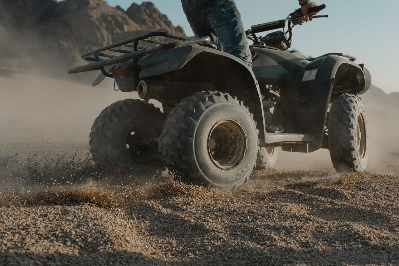 ATV rider drifting on brown sand in an off-road environment, illustrating ATV riding risks in Little Rock, AR